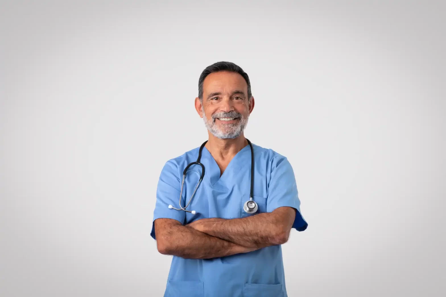 Médico idoso sorridente com jaleco azul e estetoscópio, transmitindo confiança, representando profissionais da saúde comprometidos com o bem-estar dos pacientes.