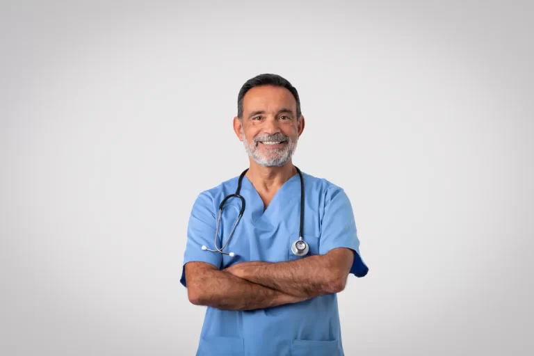 Médico idoso sorridente com jaleco azul e estetoscópio, transmitindo confiança, representando profissionais da saúde comprometidos com o bem-estar dos pacientes.