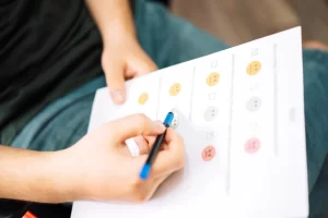Pessoa preenchendo um formulário de feedback com emojis de satisfação, utilizando uma caneta azul. Importância do feedback em ambientes de trabalho e aprendizagem.