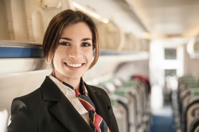 Comissária de bordo sorridente dentro de avião, símbolo de atendimento ao cliente no setor de aviação comercial. Comissário de Bordo Aposentado pode Continuar Voando?