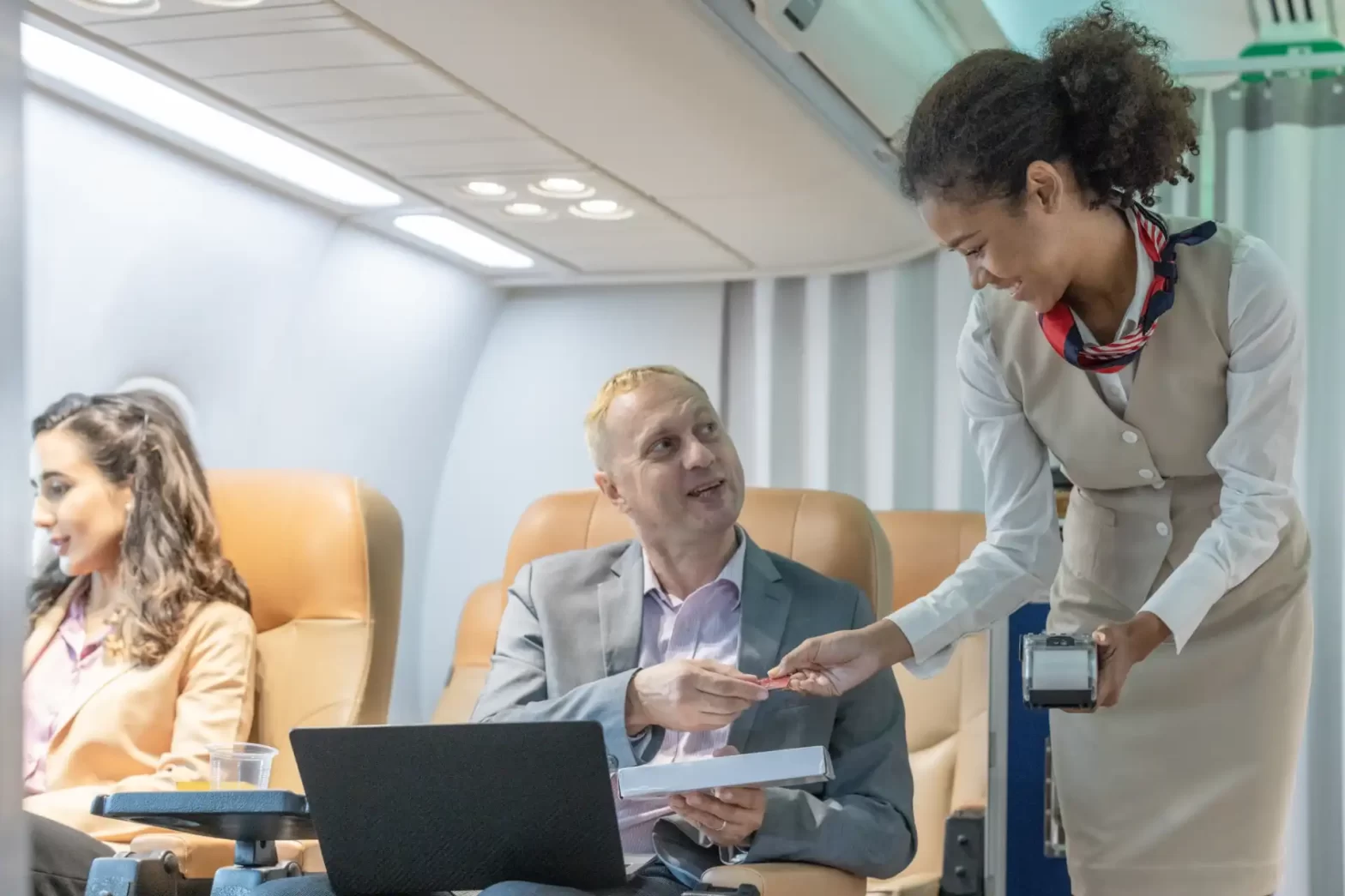 Executiva de cabine de avião atendendo passageiro durante voo, com outros passageiros ao fundo, ambiente de avião moderno e confortável. Aposentadoria do comissário de bordo por Insalubridade.