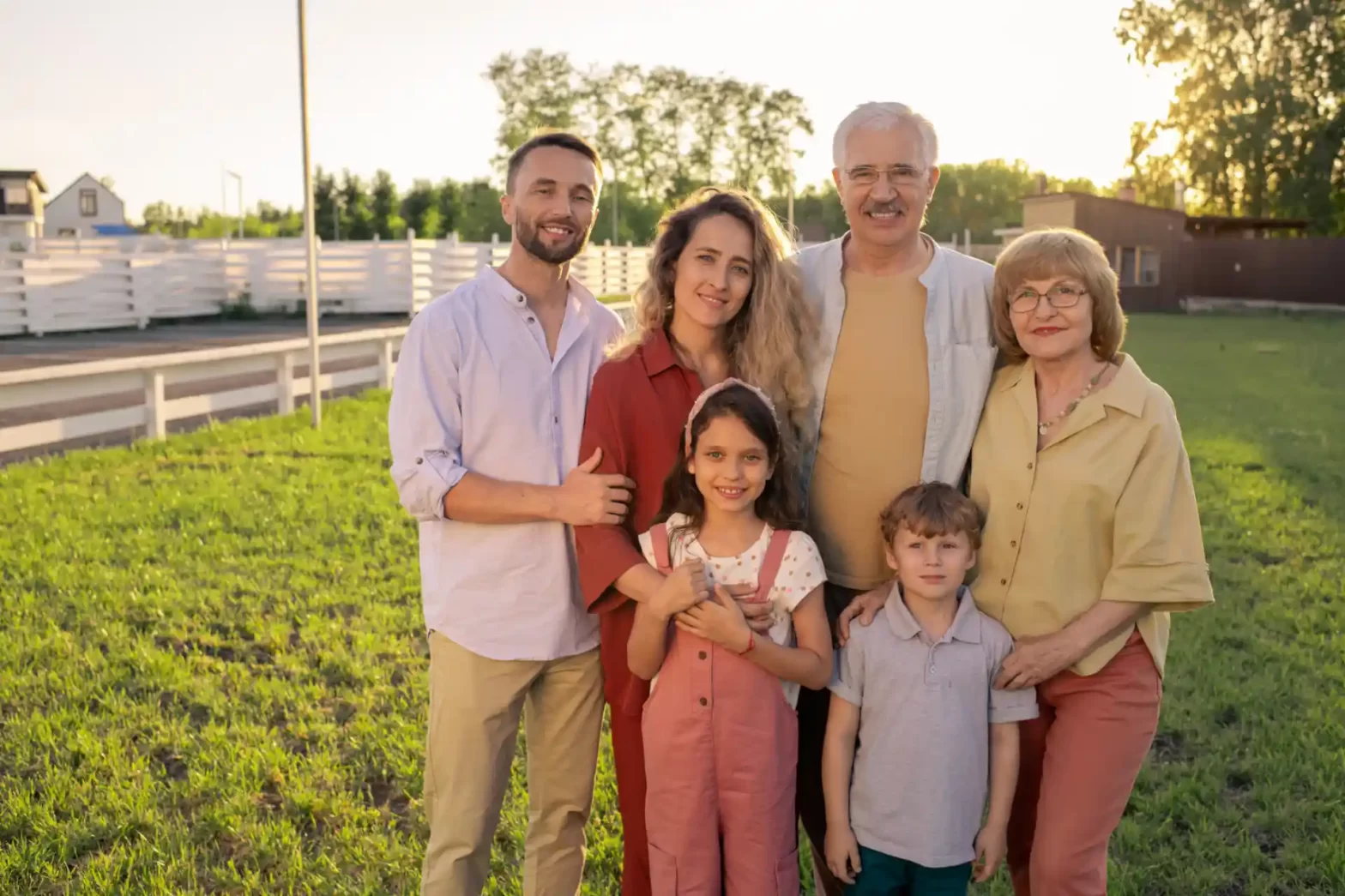 Família feliz ao ar livre desfrutando do pôr do sol em um jardim bem cuidado, representando união familiar e momentos especiais. Holding familiar.