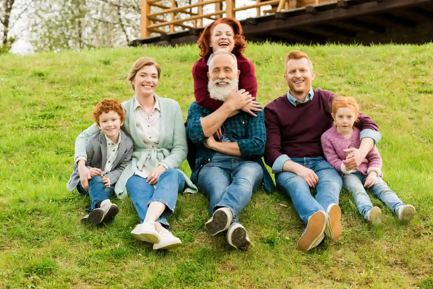 Família feliz e sorridente aproveitando um dia ao ar livre em um campo de grama verde, mostrando união e alegria. Blogpost, como abrir uma holding familiar.