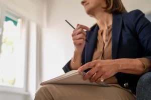 Mulher idosa pensando e escrevendo em um caderno, refletindo sobre sua vida e experiências. Blogpost o que é planejamento previdenciário.