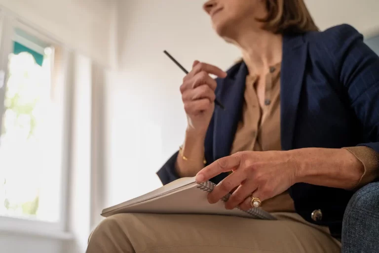 Mulher idosa pensando e escrevendo em um caderno, refletindo sobre sua vida e experiências. Blogpost o que é planejamento previdenciário.