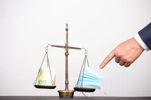 Holding Patrimonial e ITCMD. Balança antiga com uma pilha de dinheiro de um lado e máscaras faciais do outro, simbolizando o equilíbrio entre economia e saúde durante a pandemia.