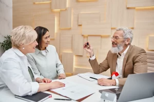 Homem apresentando produto ou ideia para duas mulheres em uma reunião de negócios, com ambiente profissional e moderno ao fundo. ADI 2446