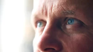 Close-up da face de um homem com olhos azuis intensos, expressão pensativa e detalhes de pele visíveis, transmitindo reflexão e foco. Post previsões para a Previdência Social no Brasil