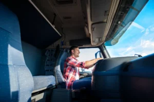 Homem dirigindo caminhonete no período diurno, sentado ao volante com as mãos no painel, enquanto observa pela cabine aberta e vê o céu ao fundo. Greve dos caminhoneiros 2026.