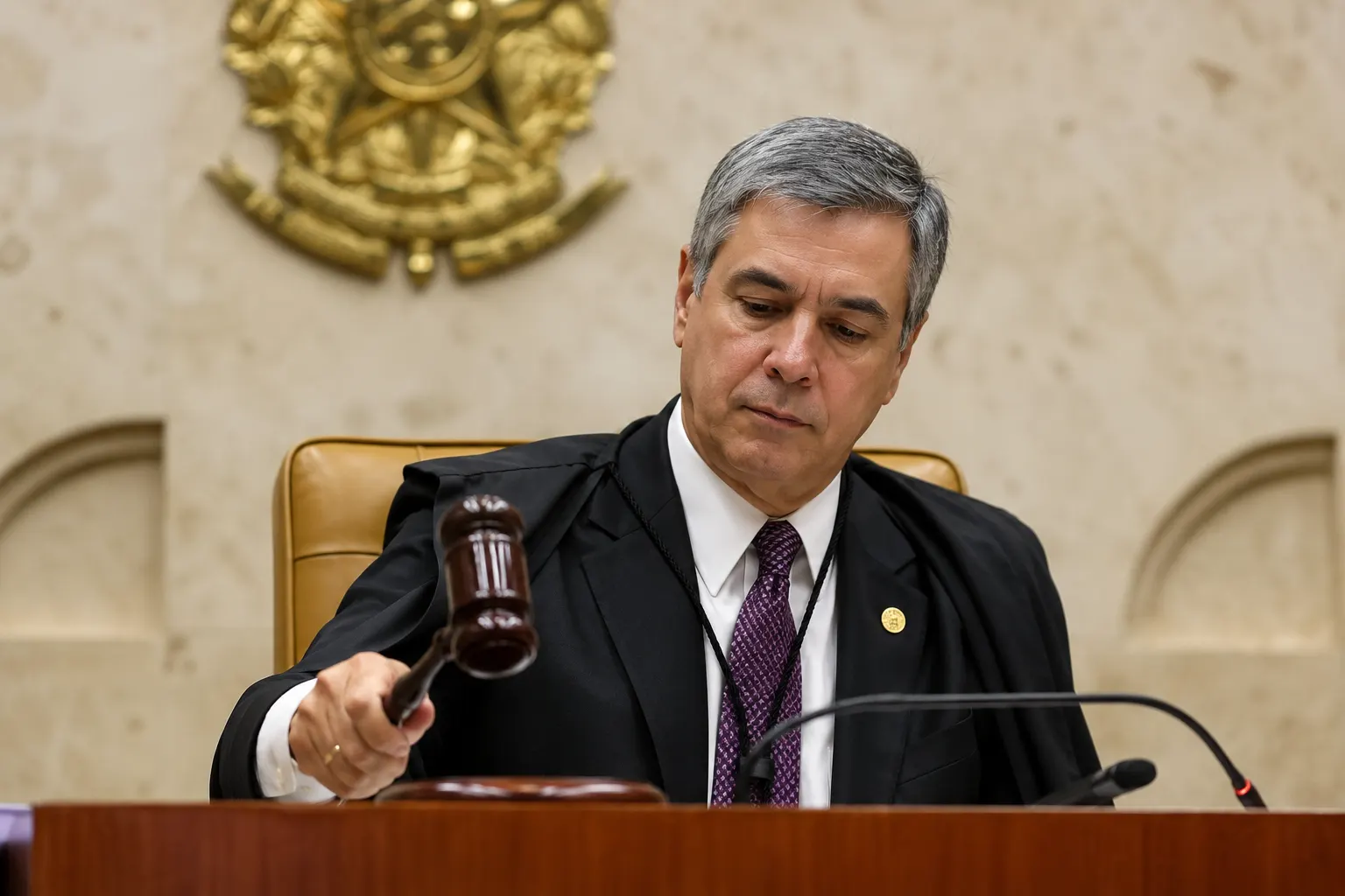 STF derruba a idade mínima da aposentadoria especial: o que muda para você. Foto de um juiz em sessão, usando toga preta e apontando com a mão enquanto sentencia ou conduz o julgamento, com martelo de juiz e brasão ao fundo.
