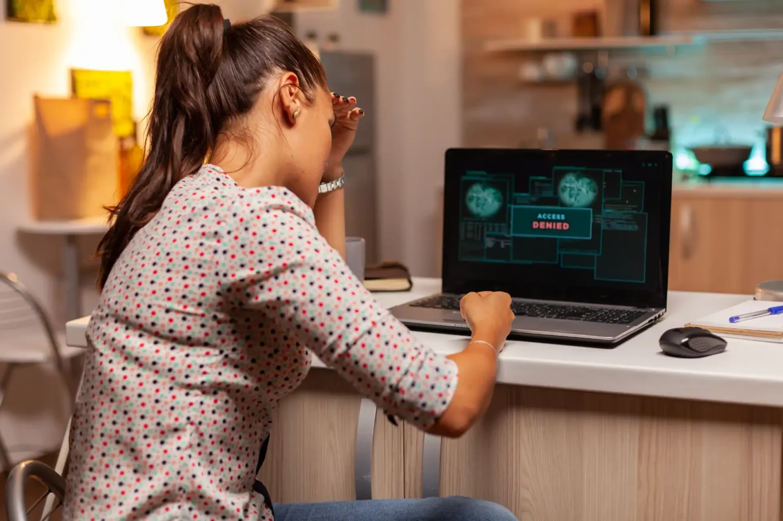 Menina trabalhando em um notebook em casa, com mensagem de “Access Denied” na tela, digitando ou treinando tarefas no computador em ambiente iluminado. Vazamento de dados.